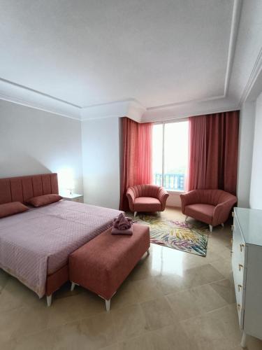 een slaapkamer met een bed en 2 stoelen en een raam bij Aria di Mare in Hammamet