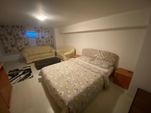 een kleine slaapkamer met een bed en een stoel bij Luka Central Apartment in Craiova