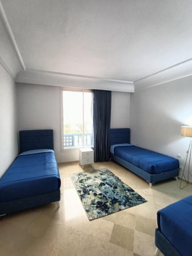 - une chambre avec 2 lits bleus et une fenêtre dans l'établissement Aria di Mare, à Hammamet