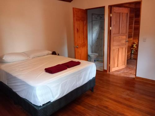 a bedroom with a bed with white sheets and a door at Aura Bungalow in Tamarindo