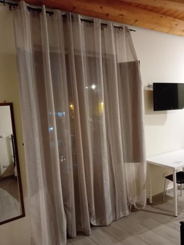 ein Fenster mit Vorhängen in einem Zimmer mit einem Schreibtisch in der Unterkunft 3 A b&b in Catania