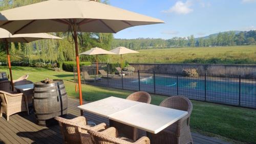 una terraza con mesa, sombrilla y piscina en Bosch Hoek Golf & Lodge, en Balgowan