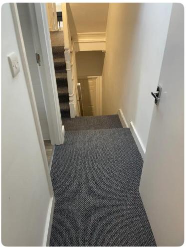 an open door to a hallway with a carpeted floor at Lovely room in Tottenham in London