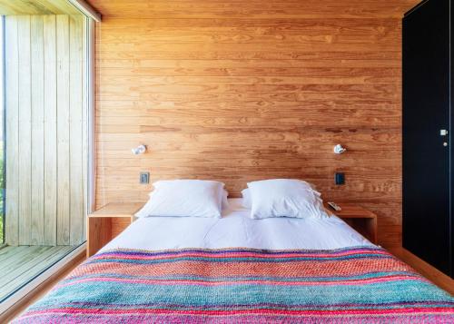 a bedroom with a bed with a wooden wall at Lodge del Mar in Pichilemu