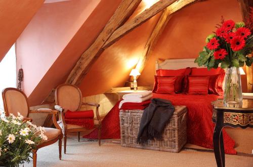 um quarto com uma cama vermelha e um vaso de flores em Une Maison, Un Jardin em Berthenay