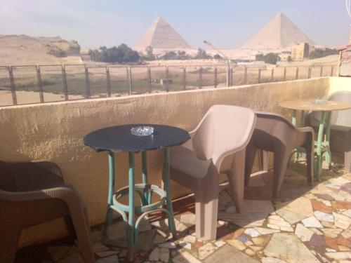 un patio con tavoli, sedie e piramidi di Anita view hotel a Il Cairo