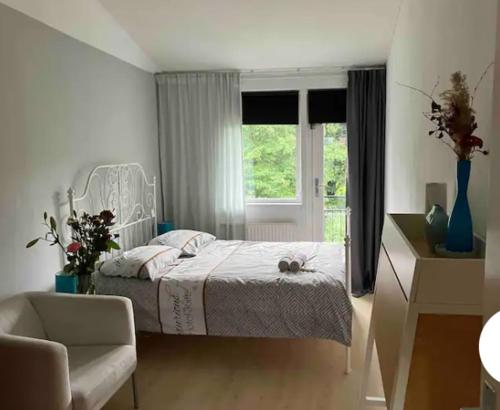 a bedroom with a bed and a chair and a window at Charming Rooms with free parking in Amsterdam