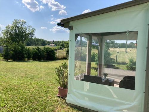 a white shed with a window in a yard at NEUTRINO VENDÉGHÁZ in Zánka