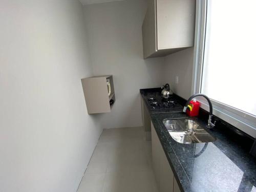 a small kitchen with a sink and a window at Ótimo Loft 50m da areia churrasq in Torres