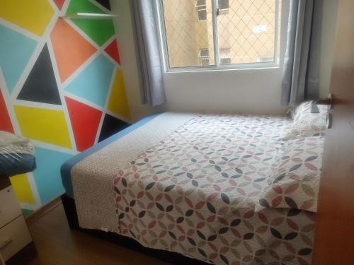 uma pequena cama num quarto com uma parede colorida em Veredas do bosque em Curitiba