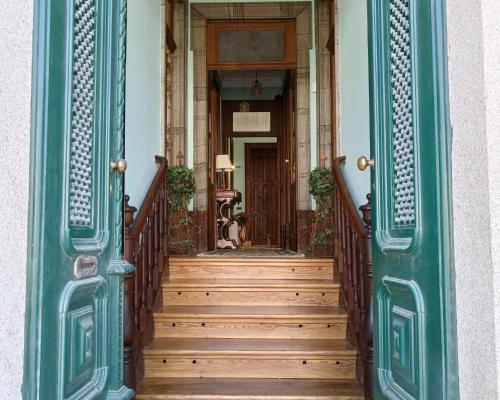 an entrance to a house with a green door and wooden stairs at Casa Brandao in Vale de Cambra