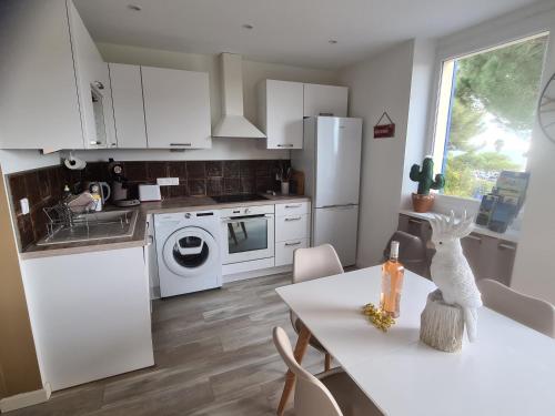 une cuisine avec des appareils électroménagers blancs et une table avec une bouteille. dans l'établissement Petit coin de paradis les pieds dans l’eau, à La Londe-les-Maures