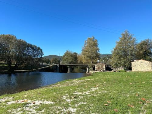 un pont sur une rivière avec un champ herbeux dans l'établissement Casa Brandao, à Vale de Cambra