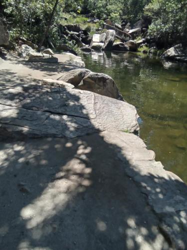 a river with a rock wall next to the water at Pousada Canto Feliz in Serra do Cipo