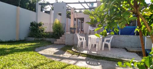 een tuin met twee witte stoelen en een boom bij COMODO DEPARTAMENTO in Encarnación