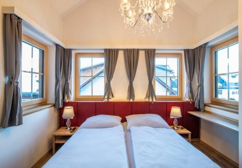two beds in a room with windows and a chandelier at Villa Elisabeth in Strobl