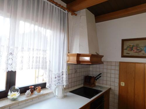 una cucina con lavandino e una finestra con tende bianche di Apartma Radlje center a Radlje ob Dravi