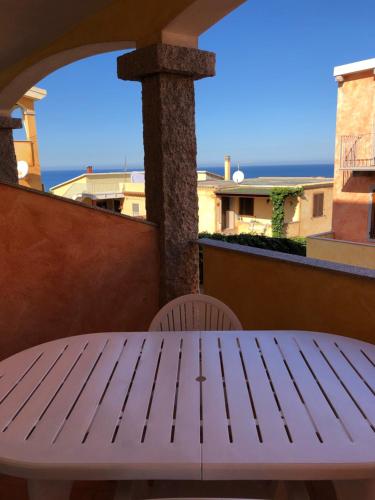 een witte tafel op een balkon met uitzicht op de oceaan bij Appartamenti Perego in Castelsardo