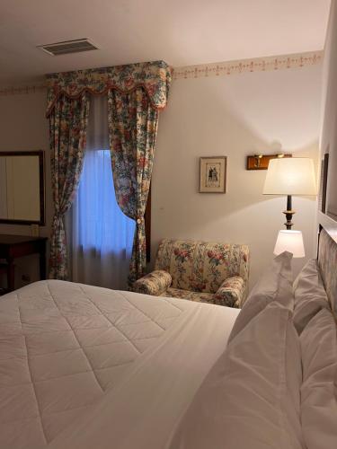 a bedroom with a bed and a couch and a window at Hotel Villa Luppis in Pasiano di Pordenone