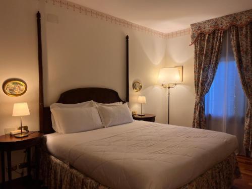 a bedroom with a bed and two lamps and a window at Hotel Villa Luppis in Pasiano di Pordenone