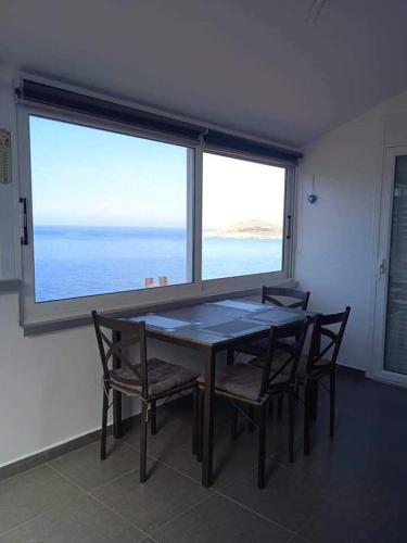 a table and chairs in a room with a large window at Kalymnos Platy Gialos Mousellis Makis Apartments in Kalymnos