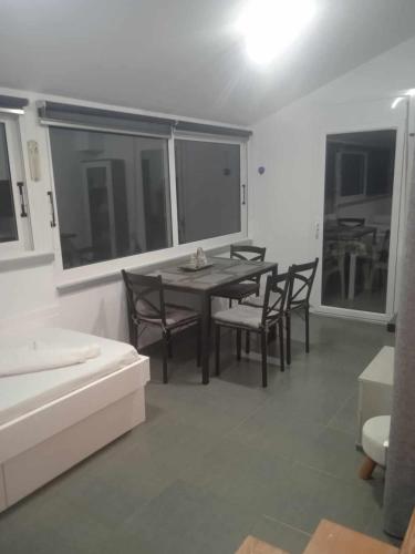 uma sala de jantar com mesa, cadeiras e janelas em Kalymnos Platy Gialos Mousellis Makis Apartments em Kalymnos