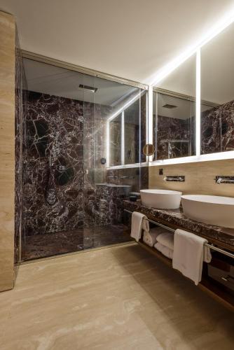 a bathroom with two sinks and a glass shower at Fendi Private Suites - Small Luxury Hotels of the World in Rome