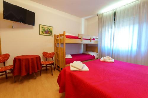 a room with two bunk beds and a table and chairs at Hotel Park Oasi in Arta Terme