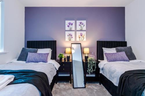 duas camas num quarto com paredes roxas em Stays Lilies House em Chester