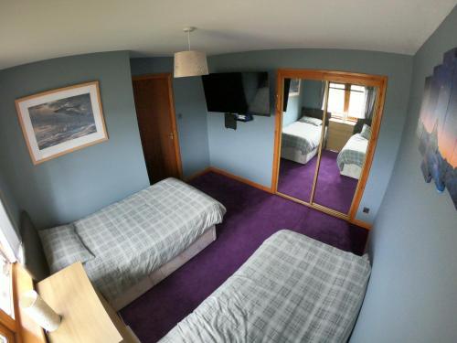 Habitación pequeña con 2 camas y espejo. en Mountain View No12, en Aviemore