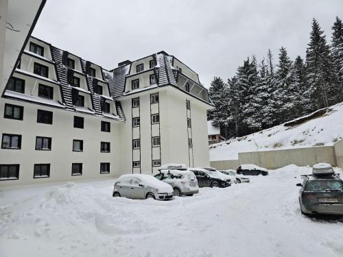 a snow covered parking lot in front of a building at Studio Leone Sunčana Planina in Kopaonik
