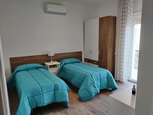 two beds in a room with blue comforter at Casa Mikaela sea view in Vieste