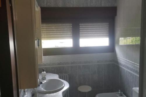 La salle de bains est pourvue d'un lavabo, de toilettes et d'une fenêtre. dans l'établissement Apartamento 3 habitaciones en casa, amplio jardín, à Liaño