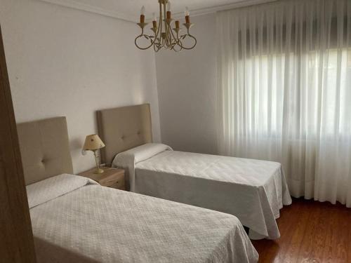 um quarto de hotel com duas camas e um lustre em Apartamento 3 habitaciones en casa, amplio jardín em Liaño