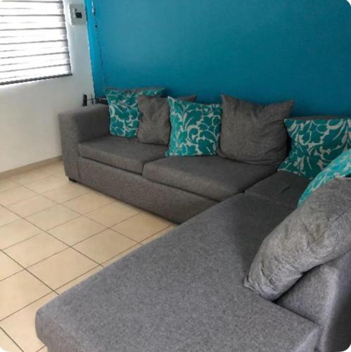 un divano grigio in un soggiorno con parete blu di Alojamiento privado con seguridad a Tepic