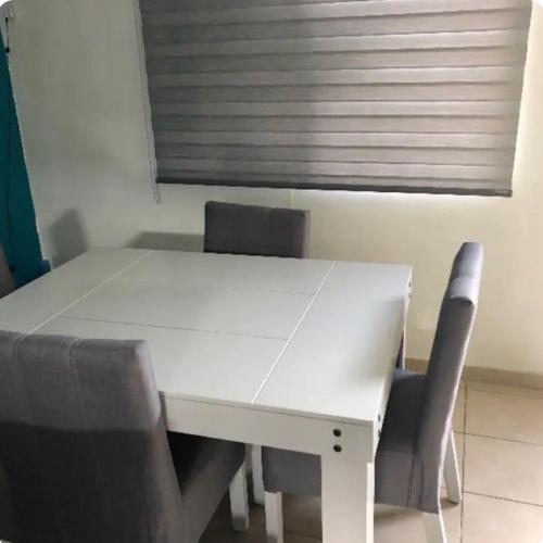 - une table et des chaises blanches dans une chambre avec fenêtre dans l'établissement Alojamiento privado con seguridad, à Tepic