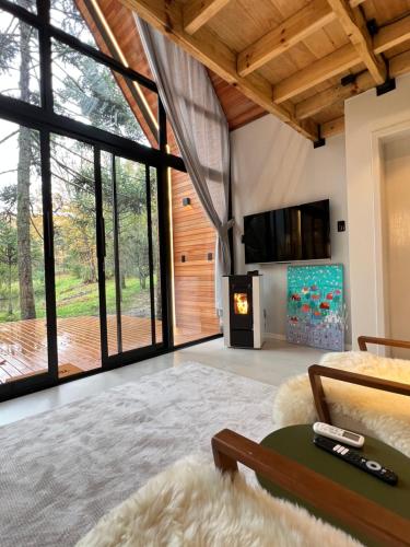 a living room with a fireplace and large windows at Cabanas Jardim de Tereza in São Joaquim