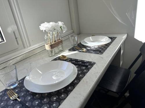 een tafel met twee witte borden en een vaas met bloemen bij NEW Studio, 2mn walk to Monaco in Beausoleil