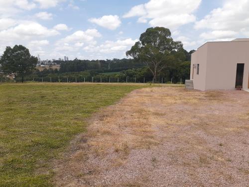 un edificio blanco en un campo junto a un campo de césped en Suítes Flor do Maracujá 02 en Ponta Grossa