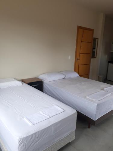 2 Einzelbetten in einem Zimmer mit Tür in der Unterkunft Suítes Flor do Maracujá 02 in Ponta Grossa