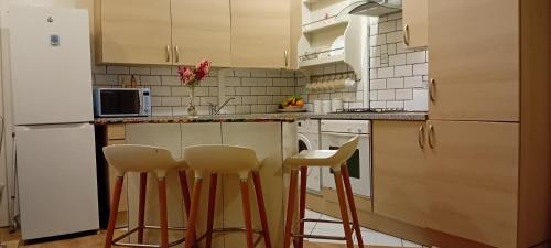 a kitchen with white cabinets and bar stools at Aaron's Holiday Home in Belfast