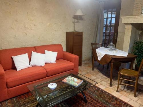 a living room with a red couch and a table at Capucine in Noyen-sur-Sarthe