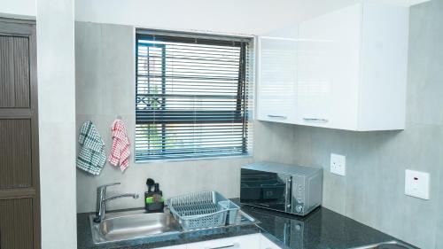 eine Küche mit einer Spüle und einer Mikrowelle in der Unterkunft Omi’s Wholesome Apartment in Mthatha