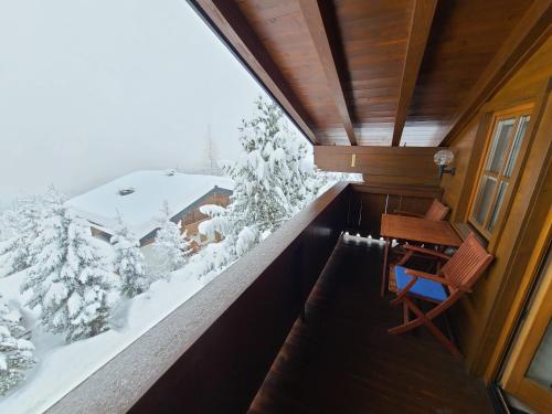 a balcony with a desk and a view of a snow covered forest at Zillertal-Arena 42m2 (2-6 persons: 2adults +4kids) in Krimml