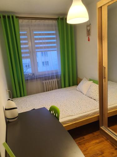 1 dormitorio con 1 cama con cortinas verdes y mesa en Biała Centrum, en Biała Podlaska