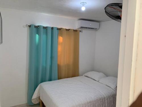 1 dormitorio con 1 cama con cortina azul en Apartamento segundo piso B en Santa Cruz de Barahona