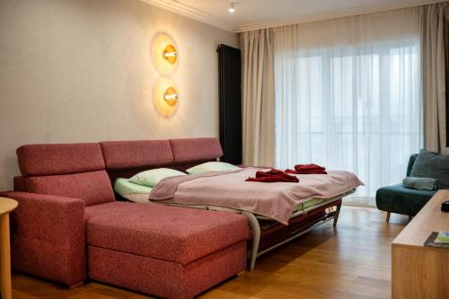 a bedroom with a red couch and a bed at Raspberry apartment and SPA in Dziwnów