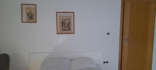 zwei Bilder hängen an einer Wand über einem Bett in der Unterkunft Hana apartman 04 in Sarajevo