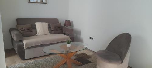 ein Wohnzimmer mit einem Sofa und einem Glastisch in der Unterkunft Hana apartman 04 in Sarajevo