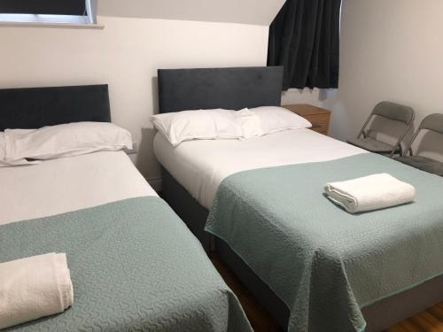 two beds with green and white sheets in a room at Callcote road Hotel in London